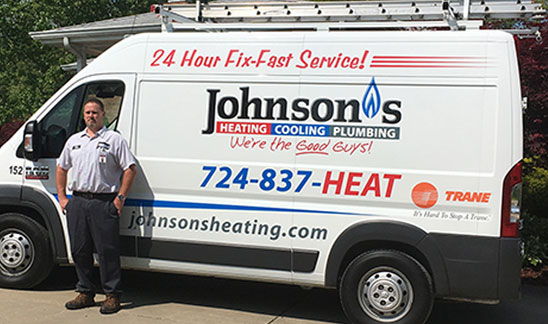 A Johnson's HVAC professional standing near his white Johnson's HVAC van.