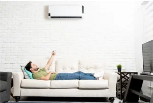 What Is A Mini Split Heat Pump?: A man sitting on his couch enjoying his mini split heat pump