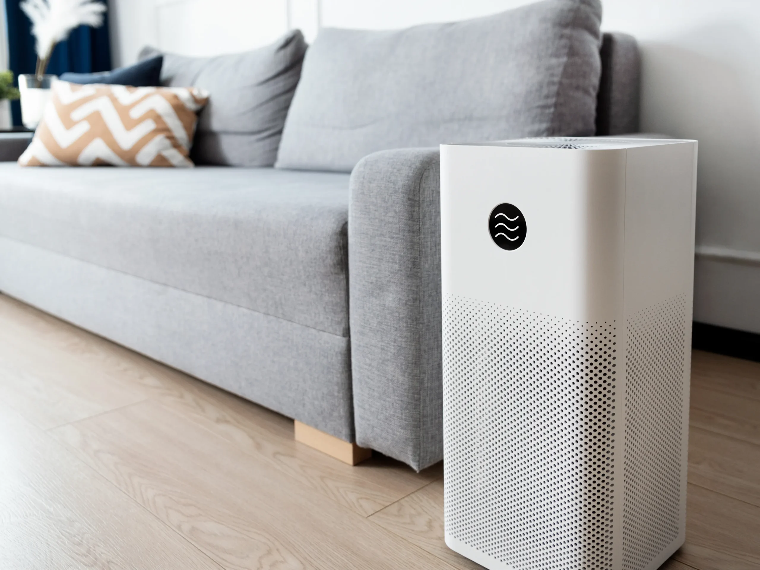 air purifier sitting next to couch - helpful tool to improve your indoor air quality