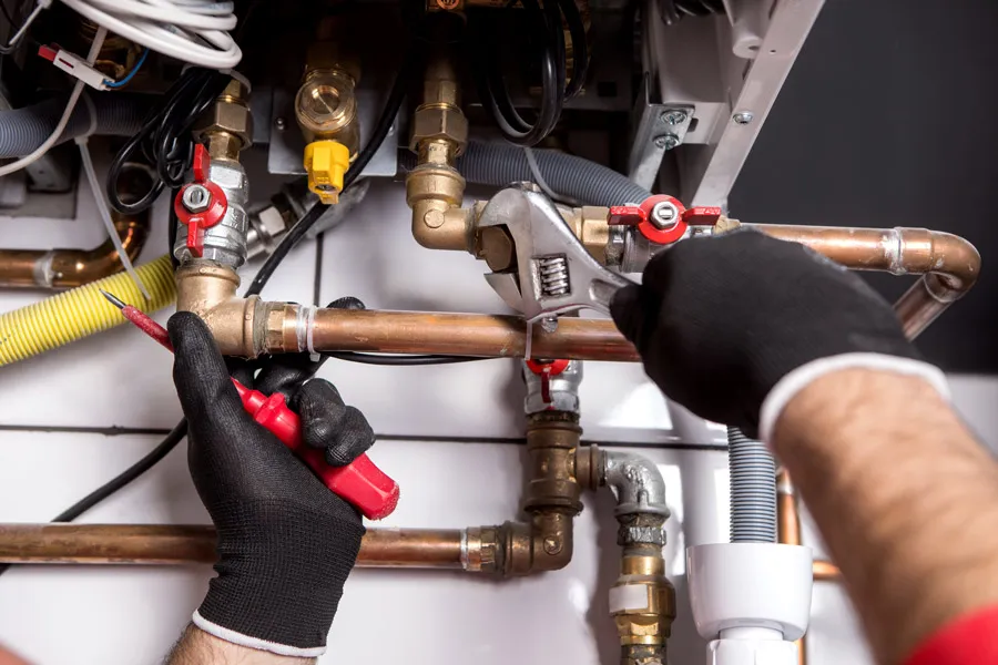 Someone in black gloves installing a heating system.